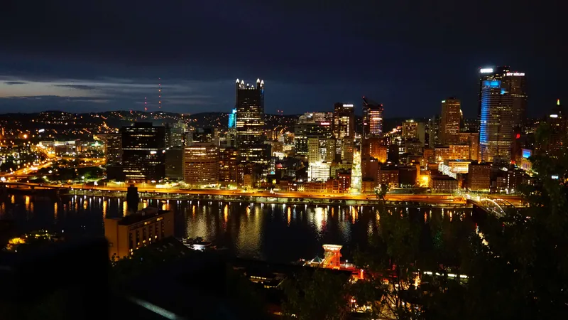 Pittsburgh skyline at night with illuminated buildings and river reflections