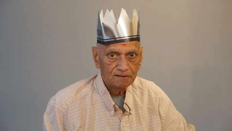 Elderly man wearing shiny silver New Year party crown portrait